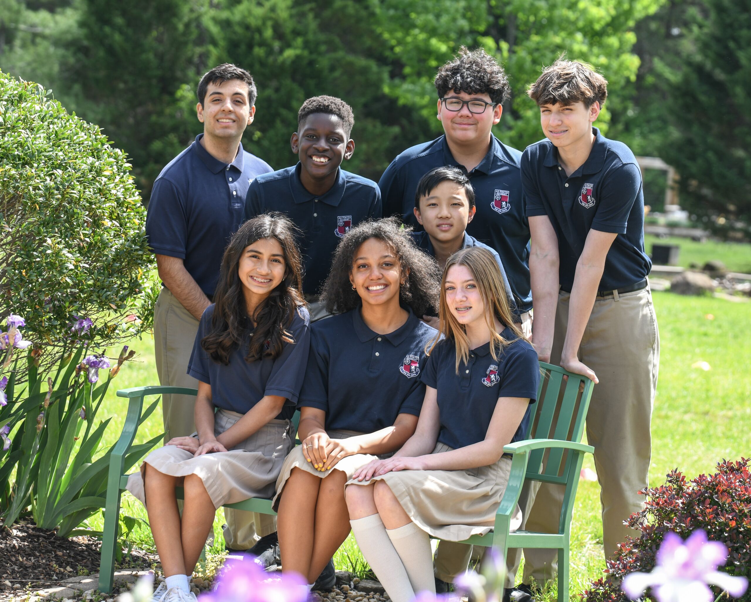 Eight Upper Campus students in uniform gathered around a garden bench